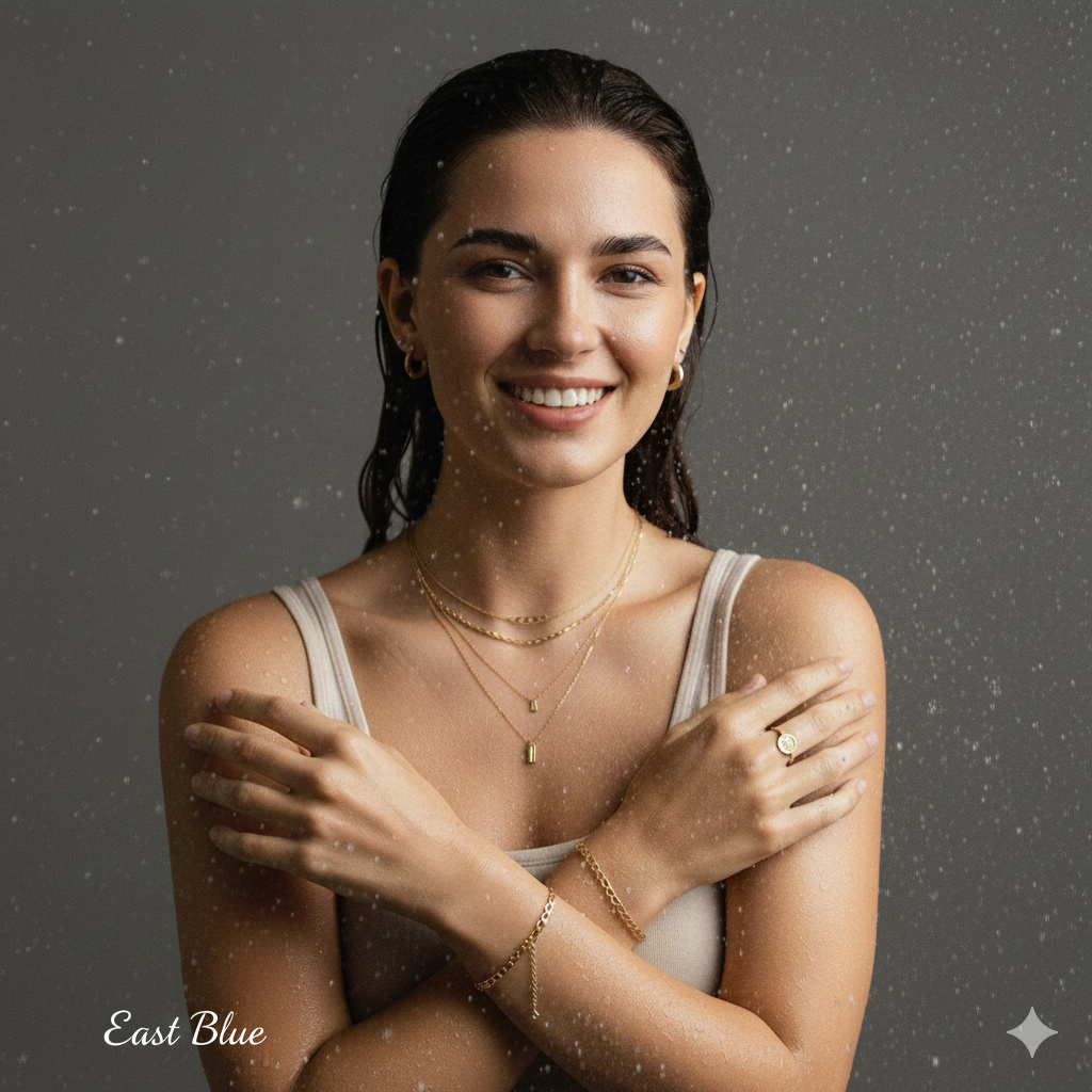 Cinematic close-up of a model wearing East Blue 18K gold layered necklaces, dainty hoop earrings, and minimal rings, featuring a realistic Sony FX3 film aesthetic with soft natural lighting.